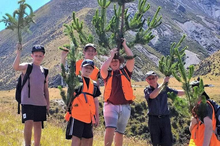 Young people from Christchurch Eco Church St Barbabas show off some of their wilding pines culled at summer camp 2020.