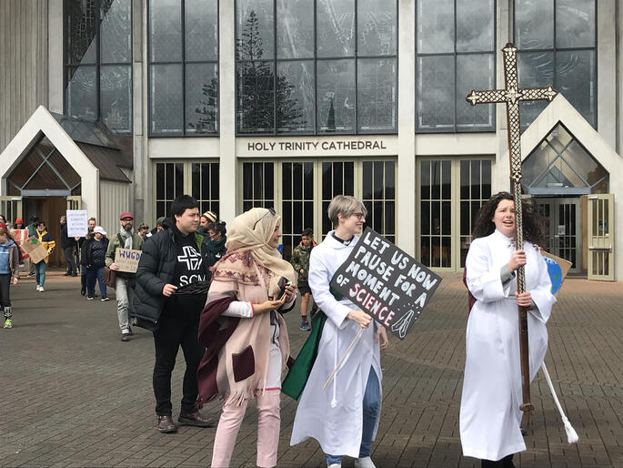 Climate strike supporters depart from Holy Trinity Cathedral led by Rev Sarah West and Jessica Hughes with Auckland's diocesan Melanesian cross.