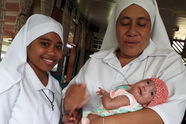 New Moana Community of St Clare postulant, Miliva Toariki smiles for the camera alongside Sr Kalolaine Tuinea'u and a new St Christopher's baby.
