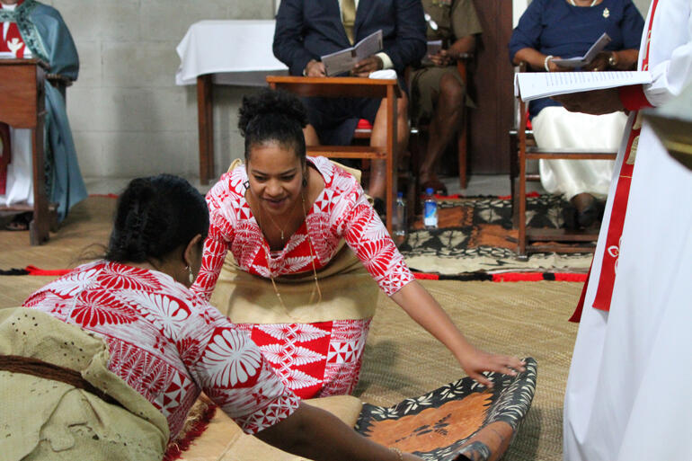 Akata Tai and friend unfurl the tapa and fine mats on which Fr Sione will be ordained.