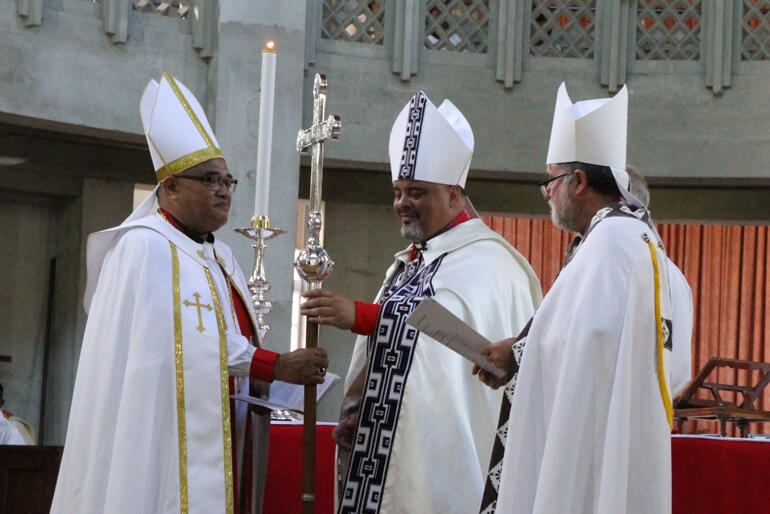 Archbishops Don and Philip hand their new fellow Archbishop the primatial cross.