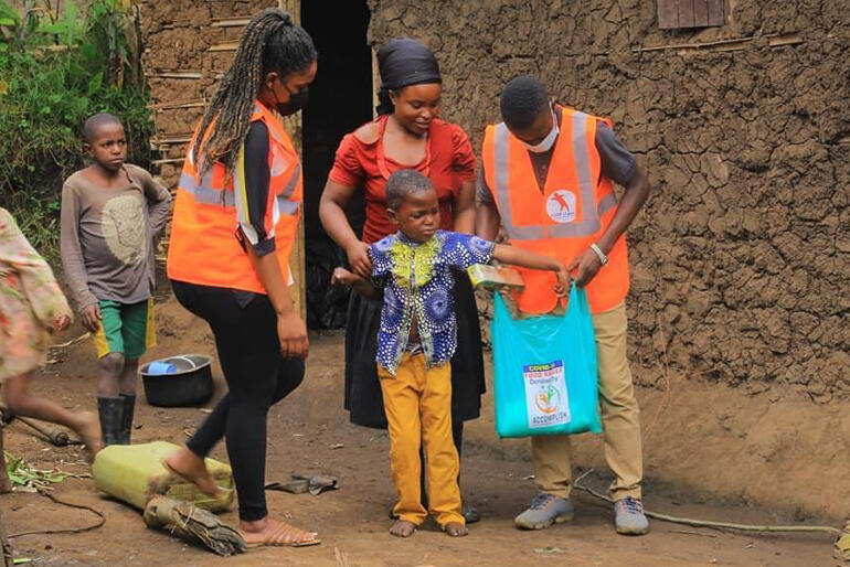 Rwenzori Special Needs Foundation workers bring a Covid-19 food pack to a child with disability and her family.